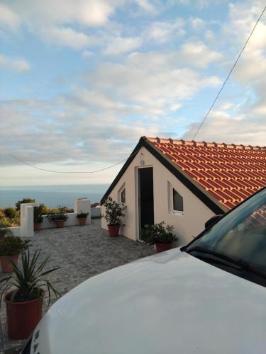 una pequeña casa blanca con techo rojo en MM House, en Bicas