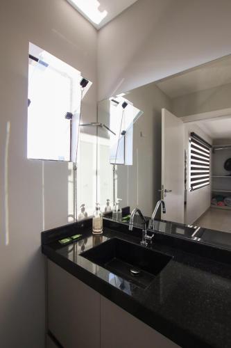 a kitchen with a sink and a large mirror at Lou Suítes 11 - City Mood, estadia leve in Guarapuava