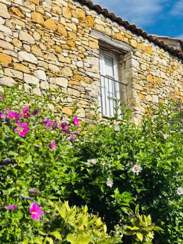a stone building with a window and flowers at L Ostau de la Treille in Limans
