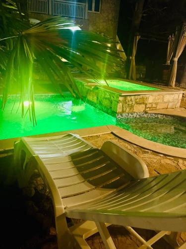 a swimming pool with a chaise lounger in the water at night at Villa Paradisio Ruheoase - Pool - Klima - Küche - Parken in Milna