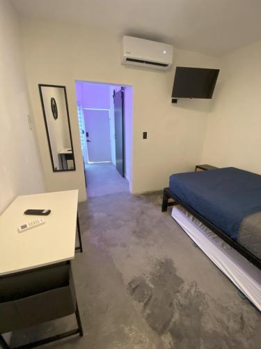a bedroom with a bed and a table and a door at DGM Lofts GPE 6 cerca Estadio Rayados in Monterrey