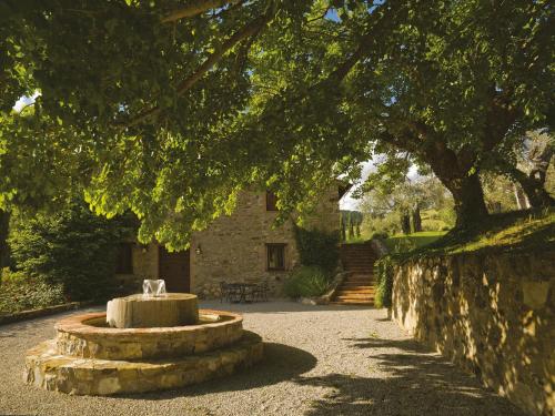 a fountain in front of a stone building under a tree at Relais Villa Monte Solare Wellness & SPA in Panicale
