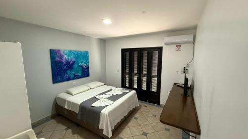 a bedroom with a bed and a painting on the wall at Pousada Caminho do Mar in Bombinhas