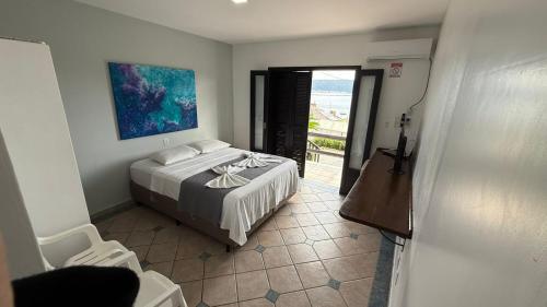 a bedroom with a bed and a view of the ocean at Pousada Caminho do Mar in Bombinhas