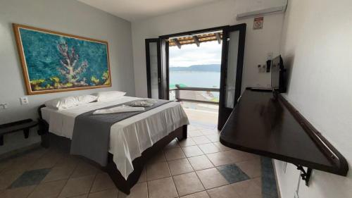 a bedroom with a bed with a view of the ocean at Pousada Caminho do Mar in Bombinhas