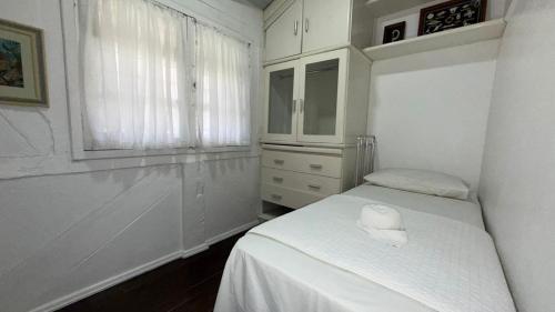 a white bedroom with a bed and a window at Pousada Caminho do Mar in Bombinhas