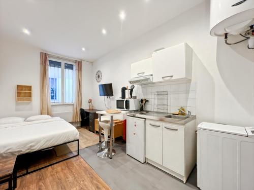 une cuisine avec des armoires blanches et un lit dans une chambre dans l'établissement Functional apartment, Belleville, Paris 11, à Paris