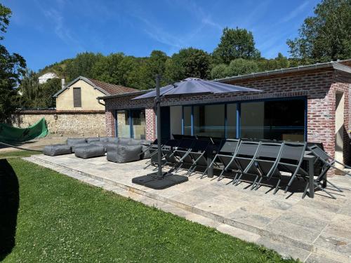 un patio con un grupo de sillas y una sombrilla en Maison des Fontainettes, en Les Andelys