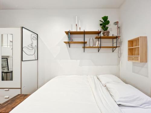 - une chambre blanche avec un lit et une étagère dans l'établissement Functional apartment, Belleville, Paris 11, à Paris