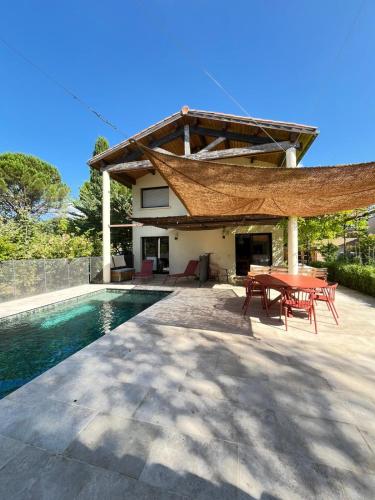 un patio avec une table et des chaises à côté d'une piscine dans l'établissement Jolie Villa spacieuse, à Saint-Clément-de-Rivière