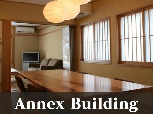 a room with a large wooden table with chairs at 越前の宿うおたけ in Echizen-shi