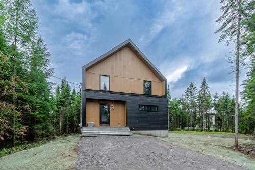 een huis in het bos met een zwarte bij Chalet Odin - SPA, PISCINE, SAUNA partagés in Valcartier Station