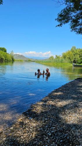 two people are swimming in a body of water at Apartments Aerodrom in Podgorica