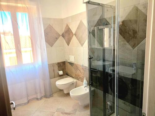 Un baño con inodoro y ducha de cristal. en Isola dei sogni, en Alghero