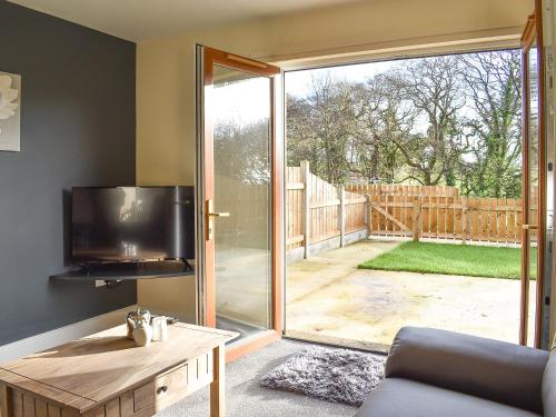 a living room with a tv and a sliding glass door at One Dorchester Drive - Uk32037 in Inglewhite