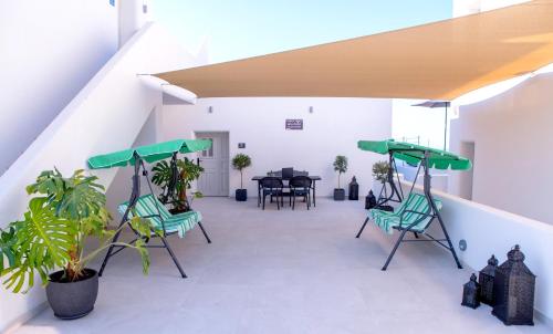 a balcony with green chairs and a table at AetherOia Suites in Oia