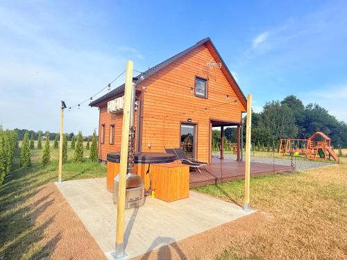 a wooden cabin with a deck and a playground at Green-Point Podlasie in Drohiczyn nad Bugiem