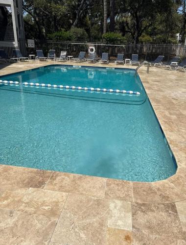 a large swimming pool with chairs in a yard at Coastal King at Seaside Villas Ocean View in Hilton Head Island
