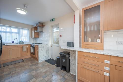 a large kitchen with wooden cabinets and a tile floor at Luton Luxury Stay in Luton