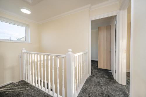 a white staircase in a home with a window at Luton Luxury Stay in Luton