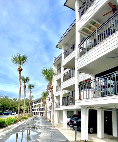 a white building with palm trees in front of it at Coastal King at Seaside Villas Ocean View in Hilton Head Island
