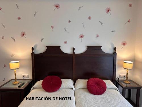a bedroom with two beds with red pillows on them at Hotel y Apartamentos La Lonja in Cangas de Onís