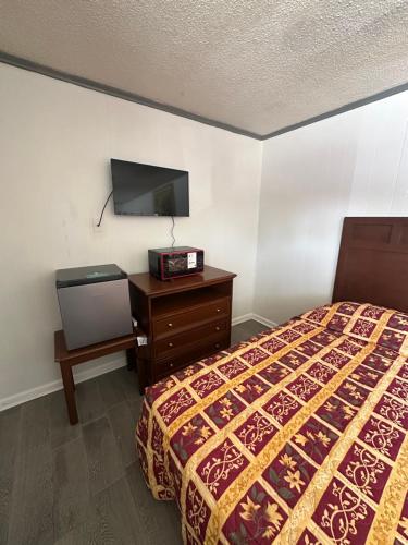 a bedroom with a bed and a dresser and a tv at Travel Inn Montgomery AL in Montgomery