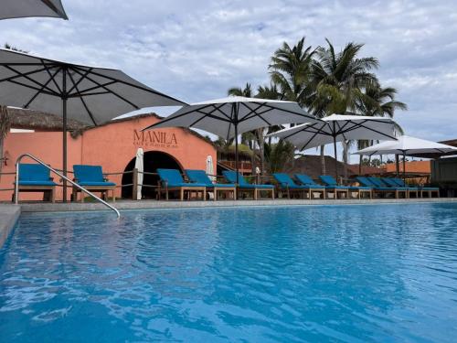 a swimming pool with blue chairs and umbrellas at La Posada Hotel Boutique in Manzanillo