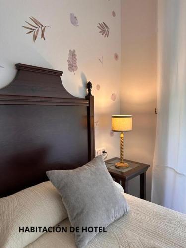 a bedroom with a bed and a table with a lamp at Hotel y Apartamentos La Lonja in Cangas de Onís