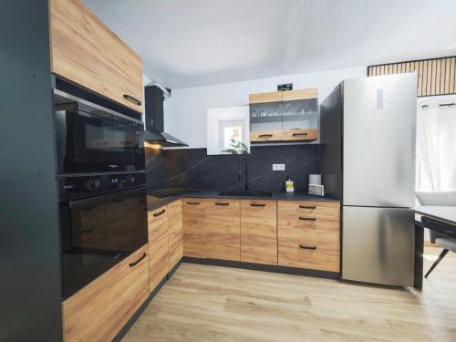 eine Küche mit Edelstahlkühlschrank und Holzschränken in der Unterkunft Casa boutique premium con diseño de autor y confort in Hinojosa del Duque