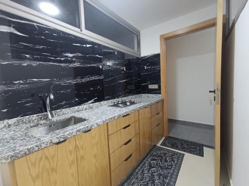 a bathroom with a sink and a black wall at BlueSea Studio's &Appart in Oualidia