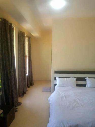 a bedroom with a large white bed and windows at New Tourist Hotel in Mwanza