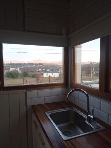a kitchen with a sink and two windows at Cabañas Altas Vistas in Sierra de la Ventana