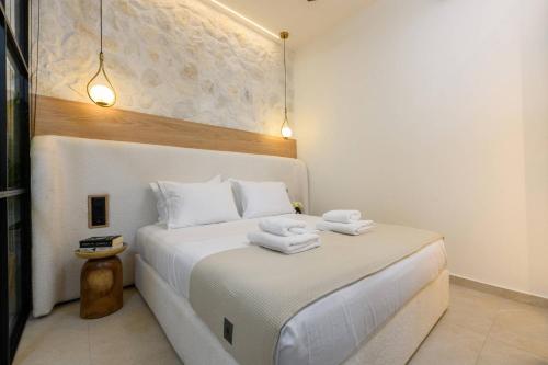 a bedroom with a white bed with two towels on it at Sentio Thassos Suites in Limenas