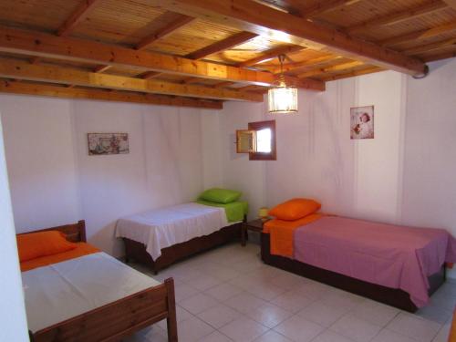 two beds in a room with wooden ceilings at Theanos House in Pigi