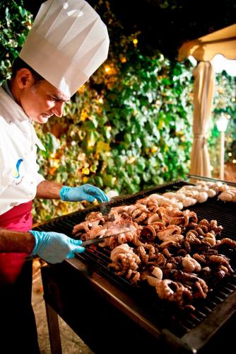 a man is cooking food on a grill at Hotel Sierra Silvana in Selva di Fasano
