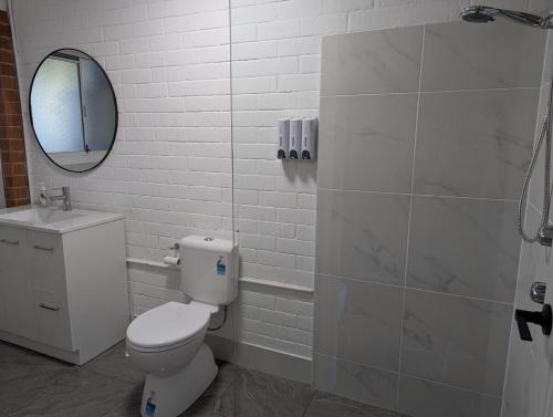 a white bathroom with a toilet and a mirror at Reel Relax Retreat at Dora Creek in Dora Creek