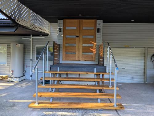 a set of stairs with a wooden door on a house at Reel Relax Retreat at Dora Creek in Dora Creek