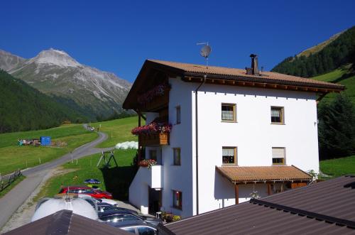 a white building with cars parked next to a mountain at Wastlhof in Malles Venosta