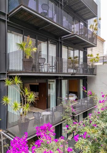 an apartment building with balconies with plants and flowers at MX Grand Suites in Mexico City