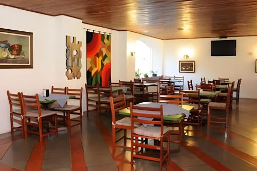 a restaurant with tables and chairs and a painting on the wall at Espaçoso Flat com Varanda no Cavalinho Branco in Águas de Lindóia