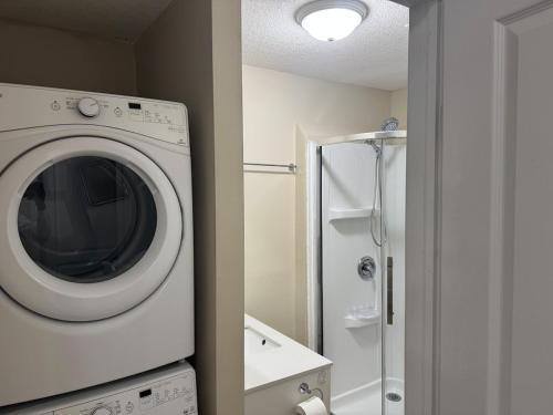 a white washing machine in a bathroom with a shower at Charming 3bedroom 3bath house in Kitchener