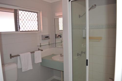 a bathroom with a sink and a glass shower at Monte Carlo Motor Inn in Townsville