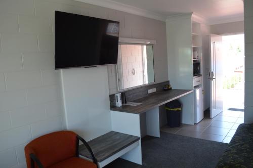 a kitchen with a desk and a tv on the wall at Monte Carlo Motor Inn in Townsville