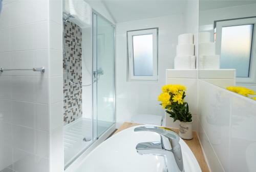 La salle de bains blanche est pourvue d'un lavabo et d'une douche. dans l'établissement Apartments & Room Rollex, à Split
