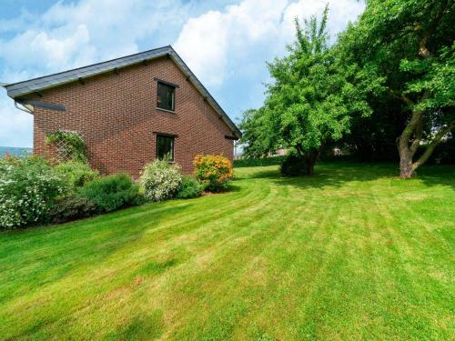 a brick house on a grassy yard with a tree at Charming cottage in heart of the Ardennes in Lierneux
