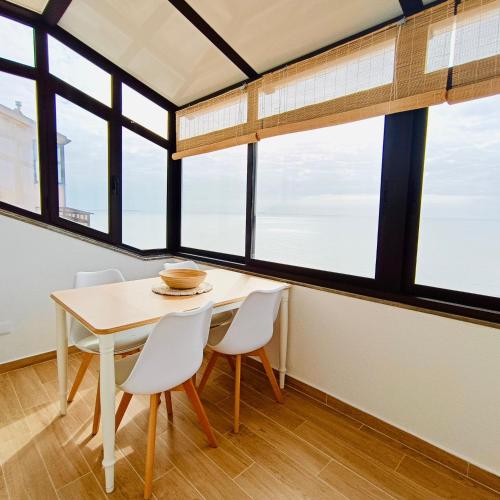 a table and chairs in a room with windows at Foz do Arelho Sunset Sea Views Apartment in Foz do Arelho