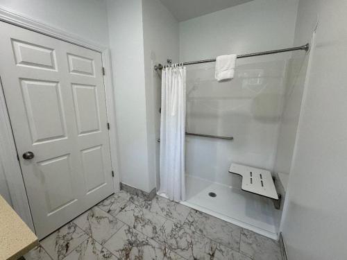 a white bathroom with a shower and a sink at Studio Motel of Lake George in Lake George