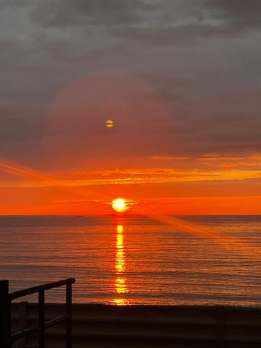 a sunset over the ocean with the sun in the sky at 琴ヶ浜琴風亭 in Ōda