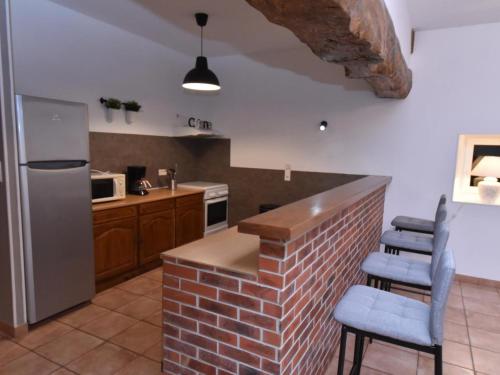 a kitchen with a brick counter with chairs and a refrigerator at Gîte indépendant avec piscine, grande terrasse, jardin, barbecue, proche St Pourçain/Sioule et Souvigny - FR-1-489-78 in Cressanges